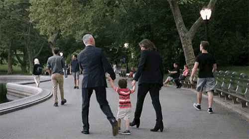 a group of people are walking down a path holding hands