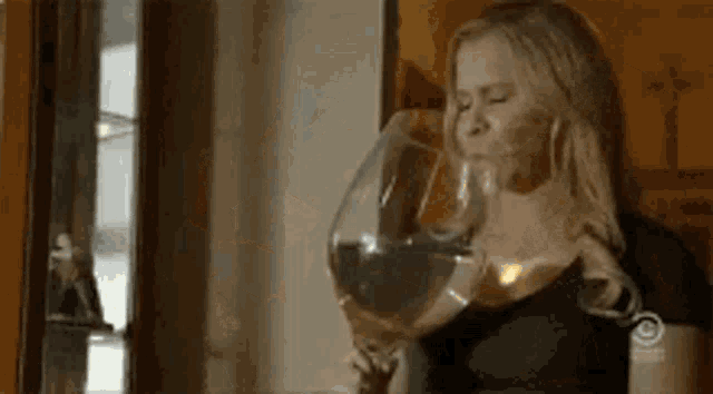 a woman is drinking a glass of wine from a large glass .