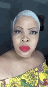 a woman with a shaved head and red lipstick is wearing a yellow dress .