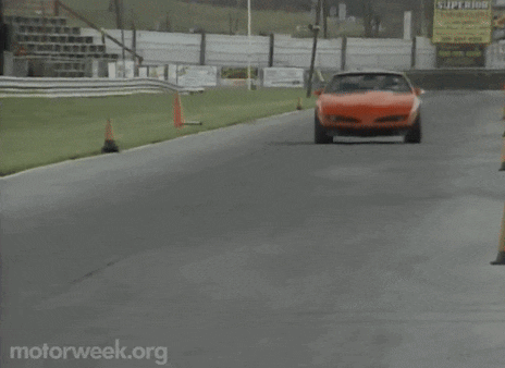an orange car is driving down a road with motorweek.org in the corner