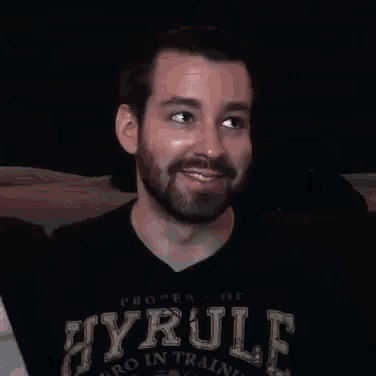a man with a beard is smiling while sitting on a couch with the word nuts written on his face .