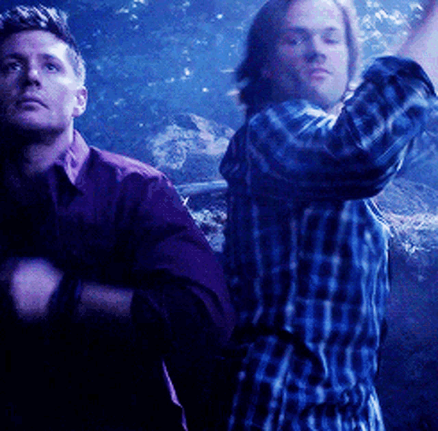 a man in a plaid shirt stands next to another man in a red shirt