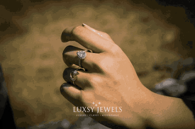 a woman 's hand with two rings on it and the words luxsy jewels