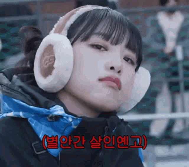 a girl wearing ear warmers and a jacket is making a funny face .