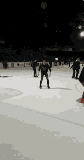 a group of people are ice skating on a rink with one wearing a sweatshirt that says sharks
