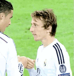 two soccer players are shaking hands on the field and one has a fly emirates logo on his shirt