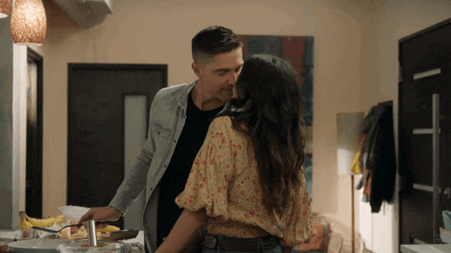 a man and woman are kissing in the kitchen