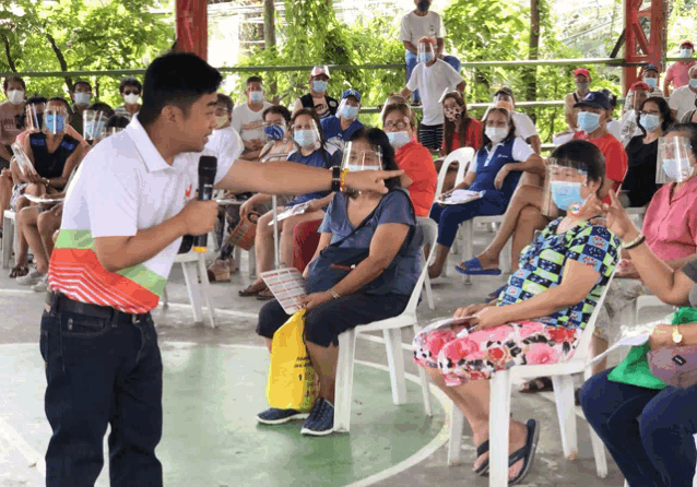 a man speaking into a microphone in front of a crowd of people
