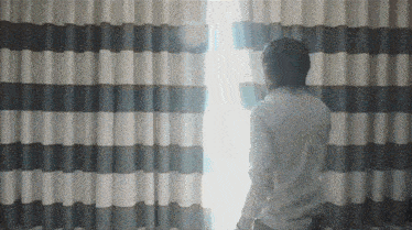 a man in a white shirt is looking out of a window