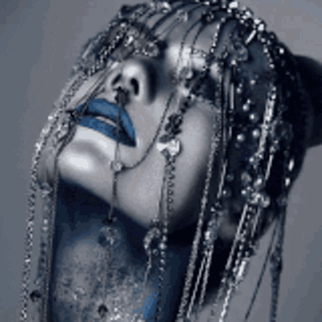 a close up of a woman 's face with blue lips and chains