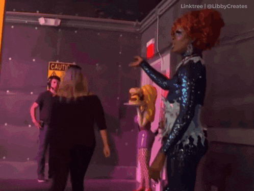 a drag queen stands in front of a sign that says " caution "