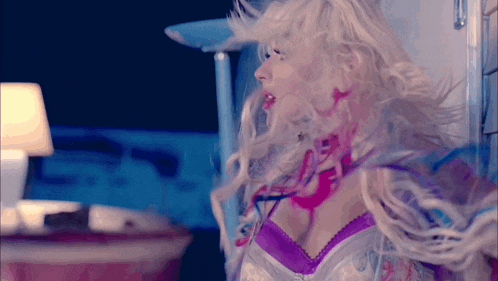 a woman with blonde hair and a purple bra is standing in a room .