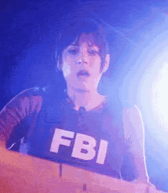 a person wearing a fbi vest stands in front of a blue light