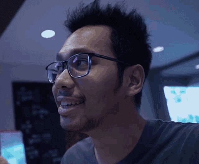 a man wearing glasses and a black shirt looks to his left