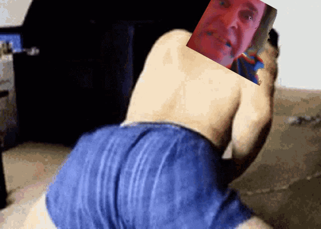a man without a shirt is kneeling down with a picture of a man on his back
