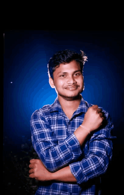 a young man in a blue plaid shirt is posing for a picture