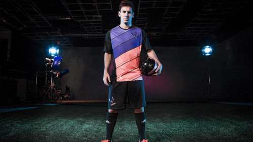 a man in a soccer uniform holds a soccer ball in his hand