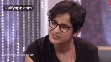 a woman wearing glasses is making a funny face while sitting on a couch .