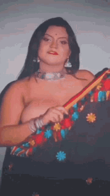 a woman without a shirt is holding a colorful embroidered saree