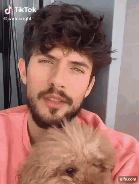 a man with a beard and mustache is holding a small dog .