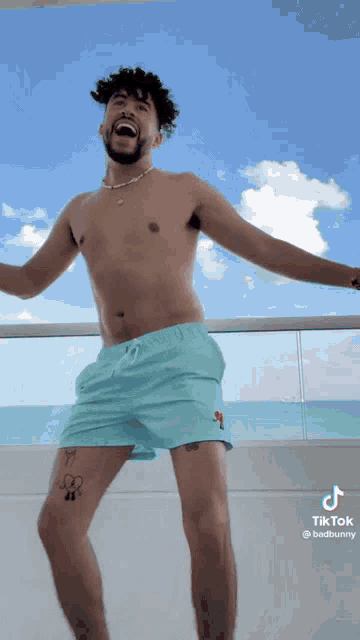 a shirtless man is standing on a balcony with his arms outstretched .