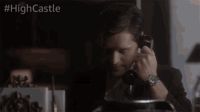 a man talking on a telephone with the hashtag #highcastle on the bottom