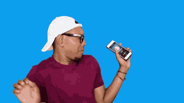 a man wearing a white hat and sunglasses is holding a cell phone with the word netflix on it