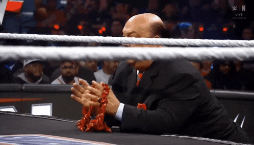 a man in a suit and tie is sitting in a wrestling ring with a rope around his face