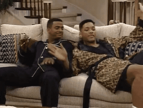 two men are sitting on a couch wearing pajamas and leopard print robes .
