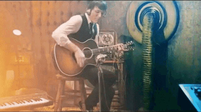 a man playing a guitar in a room with a keyboard