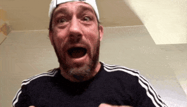 a man with a beard is making a funny face with his mouth open .