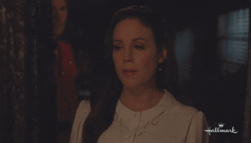 a woman in a white top is looking at a man in a red shirt with the words hallmark on the bottom right