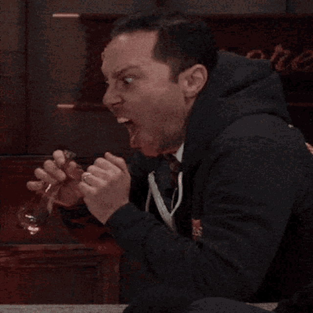 a man sitting at a table with his mouth open holding a glass