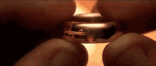 a close up of a person 's hands holding a ring with the word elvish on it .
