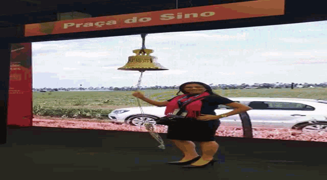 a woman is standing in front of a large screen that says praca do sino