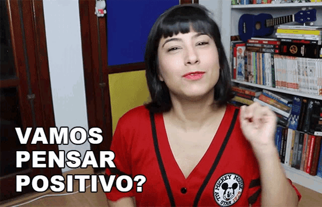 a woman wearing a red shirt that says mickey mouse on it says vamos pensar positivo