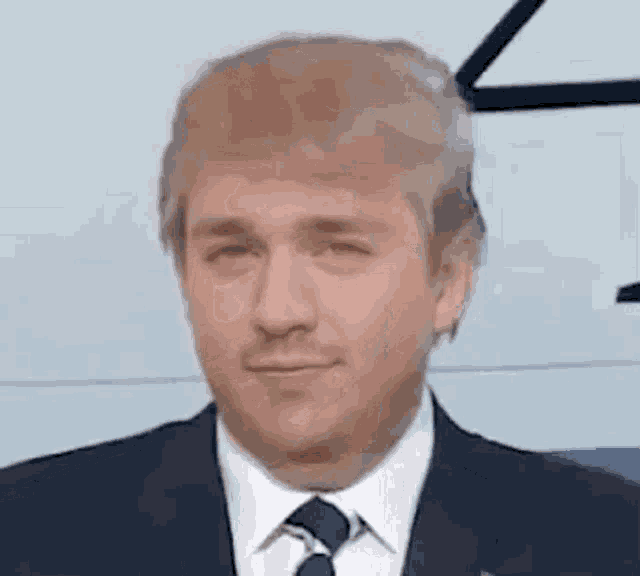 a man in a suit and tie is looking at the camera with his eyes closed .