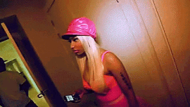 a woman wearing a pink hat holds a cell phone
