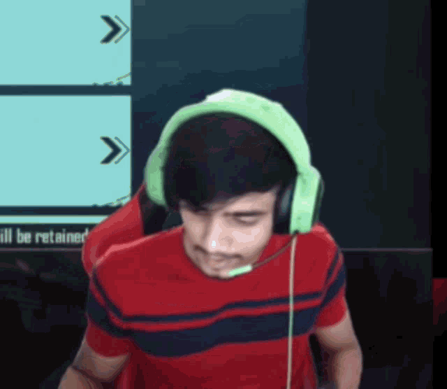 a man wearing green headphones is sitting in front of a screen that says ' ill be retained ' on it