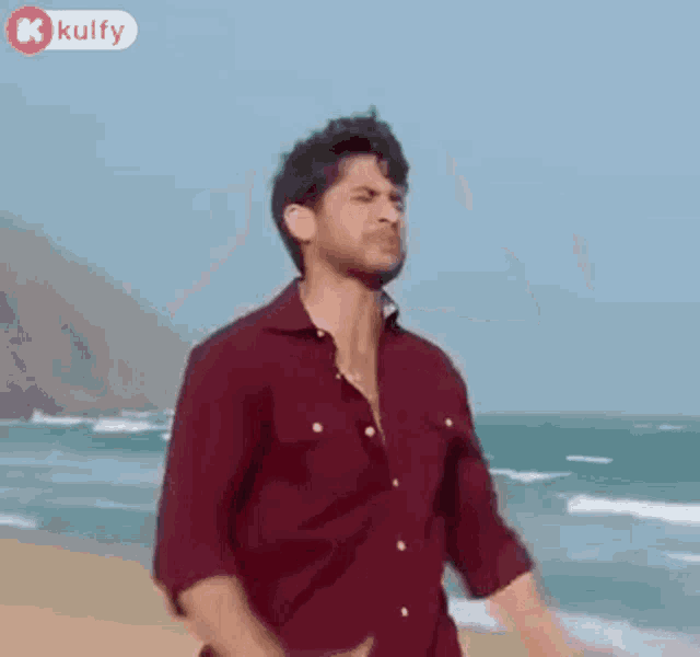 a man is standing on a beach with his hands on his head and making a funny face .