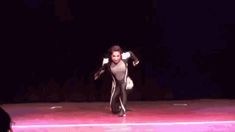 a woman in a black and white outfit is kneeling on a stage