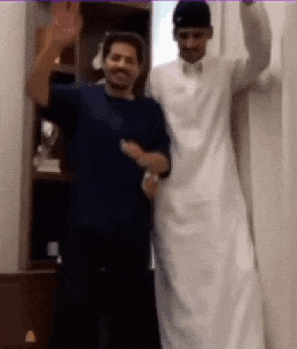 two men are standing next to each other in a room and dancing .