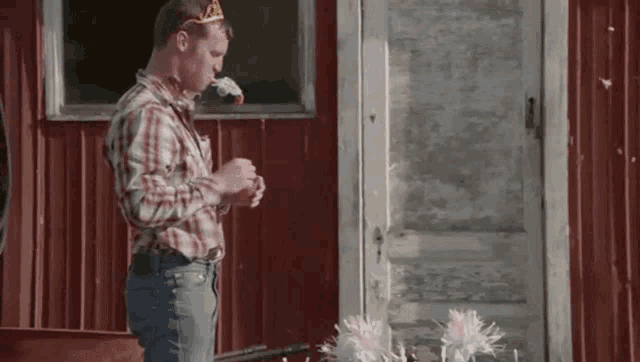 a man wearing a crown is standing in front of a red wall .