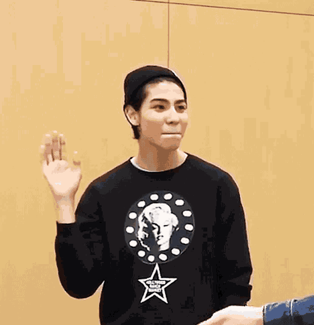 a man wearing a black shirt with a star on it waves