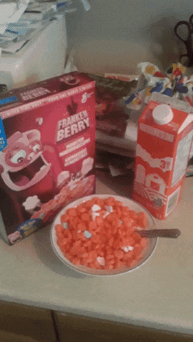 a box of franken berry cereal sits on a counter next to a bowl of cereal