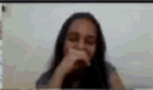 a woman is covering her mouth with her hand while talking on a video call .