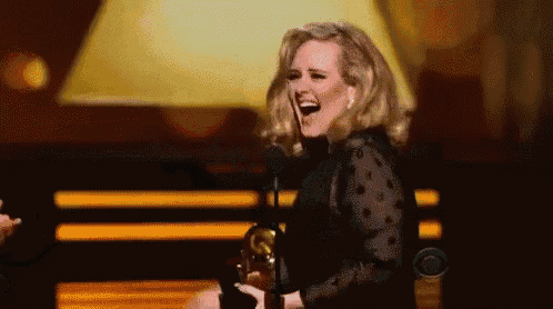 a woman is laughing on a stage while holding an award .