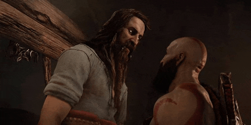 a man with long hair and a beard is standing next to another man with a beard in a dark room .