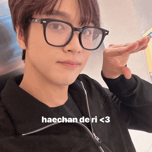 a close up of a person wearing glasses with the words haechan deri < 3 below them