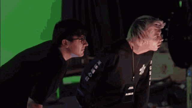 two men standing next to each other in front of a green screen